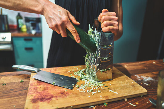 Man Grating a Zucchini on a Box Grater on a Cutting Board