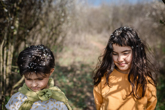 Two Sisters Smiling with Spring Blossom Petals in Their Hair Outdoors