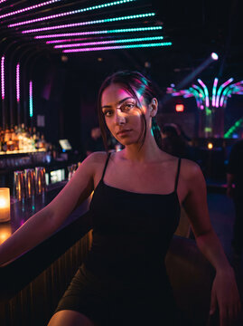 portrait of a woman poised in a black dress, nightclub theme