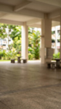 Vertical blurred Singapore HDB void deck with pillars and garden background, empty center for presenter