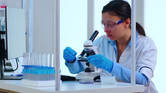 Microscope, specimen and slide placement by woman scientist preparing optical examination in a laboratory, with gloved hands working on sample analysis, biological research and experimental accuracy.