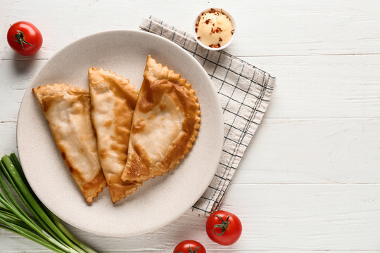 Traditional chebureki fried pastries, authentic eastern european cuisine and comfort food served with fresh tomatoes and sauce on a rustic wooden table