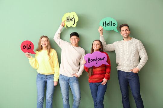 Group of young people holding speech bubbles with words HELLO in different languages on green background