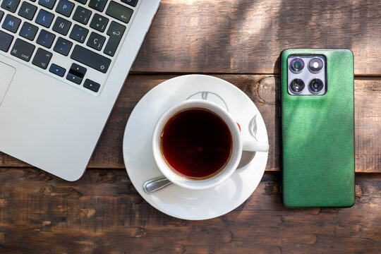 Top view of coffee cup, laptop computer, and smartphone on wooden table