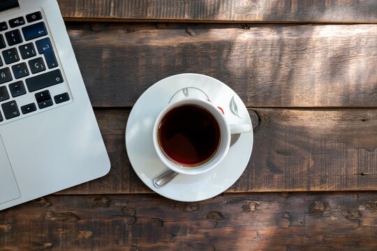Top view of coffee cup and laptop on rustic wooden table