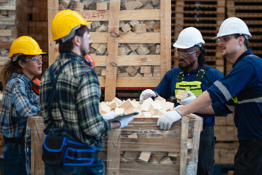 Wood offcuts in a crate are inspected by three men and a woman discussing wooden blocks inside the lumber warehouse.