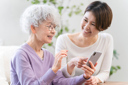 若い女性にスマートフォン操作を習うシニア女性