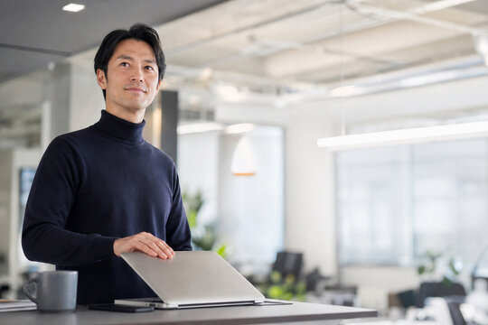オフィスでノートパソコンを閉じる日本人男性
