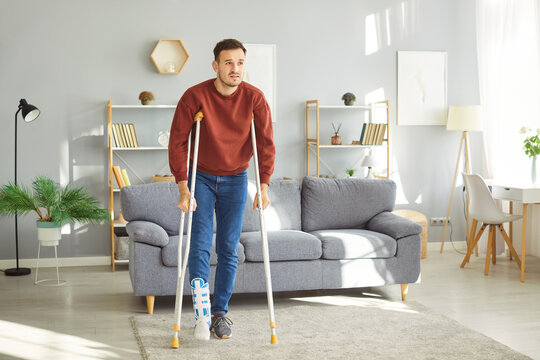 Broken leg or foot injury trauma man walking on crutches with bandaged leg at home, patient on rehabilitation period, painful swollen foot, not be able to walk on it, severe fracture, protective cover