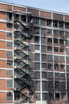A prefabricated apartment building with a charred facade and broken windows.
