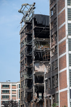 A prefabricated apartment building with a charred facade and broken windows.