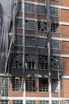 A prefabricated apartment building with a charred facade and broken windows.