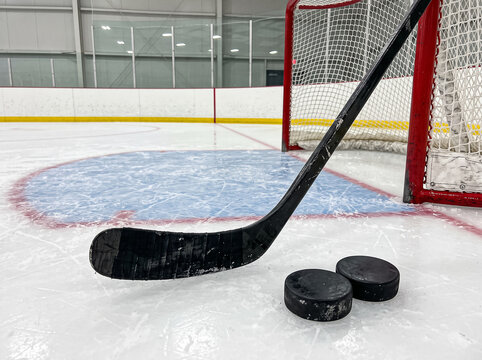 hockey stick and pucks on ice near gates