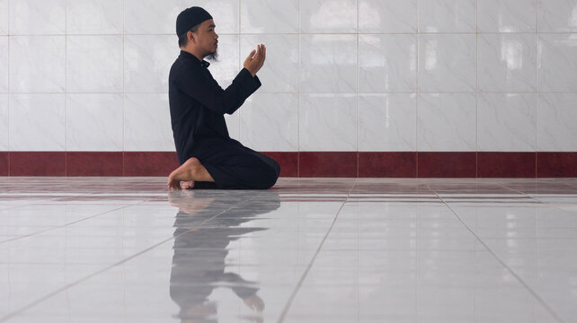 Man Performing Dua in Tiled Prayer Room