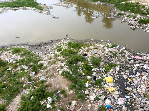 Polluted Riverbank with Plastic Waste and Debris