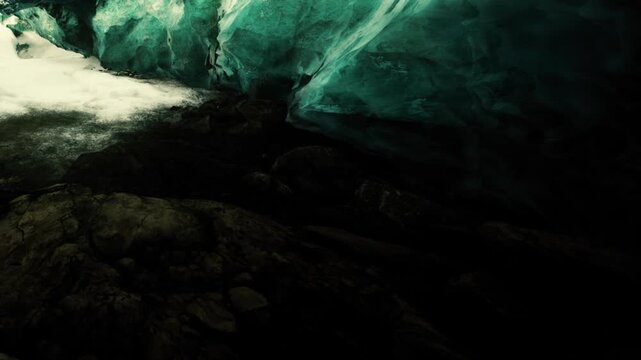 Natural glacial cave interior featuring glowing turquoise ice walls and dark volcanic rock formations on the ground during daylight