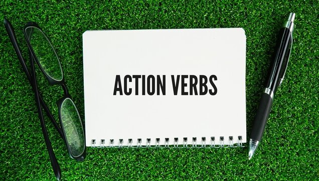 Pen, glasses and paper with the word action verb is a word that describes a physical or mental action performed by the subject of a sentence.