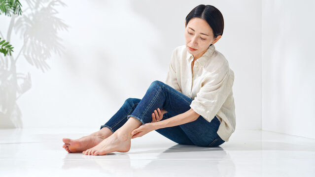 足をさする女性。痛み、筋肉痛、疲れ、疲労、ふくらはぎ、関節痛、マッサージ、フットケア、リラックス