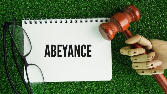 Judge's gavel and paper with the word Abeyance refers to a state of temporary inactivity, suspension, or a hold on an action, plan, right, or title while waiting for a future event or decision to occu