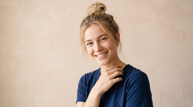 Jeune femme souriante avec main pr&egrave;s du cou en portrait sur fond beige
