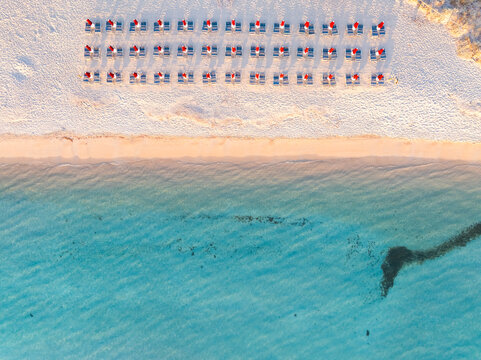 Aerial view of red beach umbrellas and turquoise sea at Porto Taverna, Sardinia