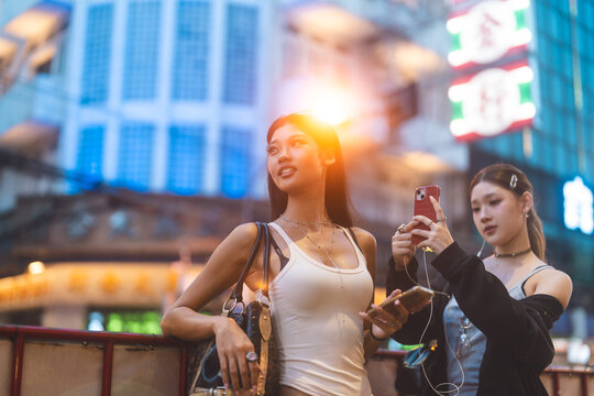Two young asian women using smart phone wear gen Z street fashion style outfit travel in Bangkok