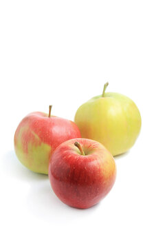 Group of three fresh organic apples including two red and one yellow green fruit isolated white background