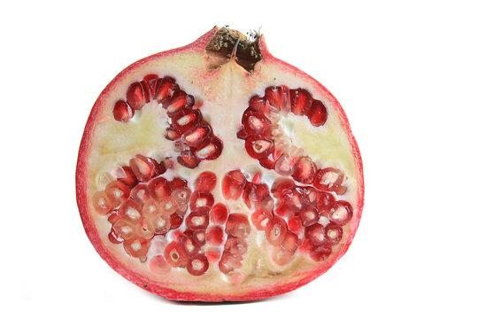 Front view of ripe red pomegranate fruit half cross section showing juicy seeds isolated white background
