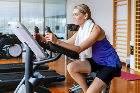 Focused woman training on stationary exercise bike at gym