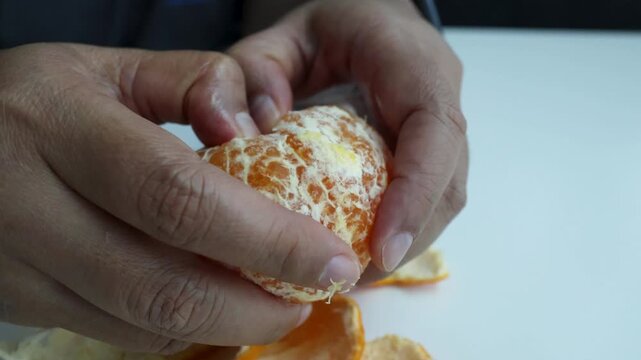 Hands Splitting Open a Peeled Ripe Mandarin Orange