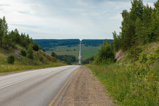 Straight asphalt highway stretching through green rolling hills in Bashkortostan Russia