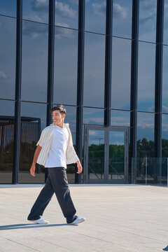 Young man walking smiling in modern urban environment
