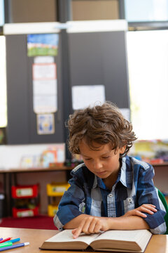 Schoolboy reading a book in the classroom