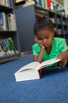 Schoolgirl reading a book in the library