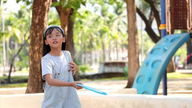 Little Girl Throws a Flying Disc at an Outdoor Playground