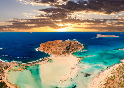 Aerial photo of Balos beach lagoon with turquoise shallow water, white sand and peninsula in Crete, Greece at sunset