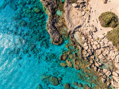 High angle drone view of Elafonisi sandy beach shoreline with crystal clear turquoise sea in Crete, Greece.