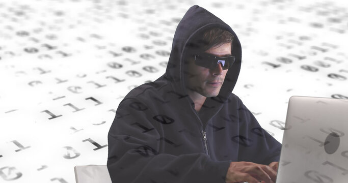 A male hacker digitally composes on a laptop amidst binary code for online security.