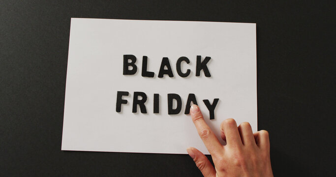 Hand moving black friday text in black letters on white rectangle with black background