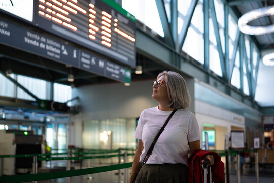 White woman waiting at airport departure ticket counter with luggage