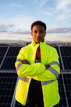 Man in high visibility jacket in front of solar panels at sunset