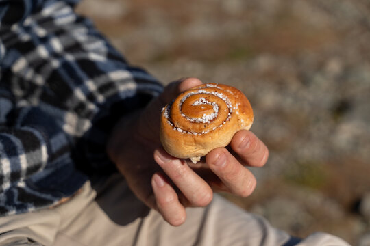 Hand holding cinnamon roll outdoors