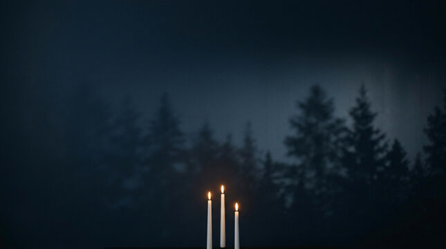 White candles burning against a dark misty forest background. Peaceful spiritual concept.