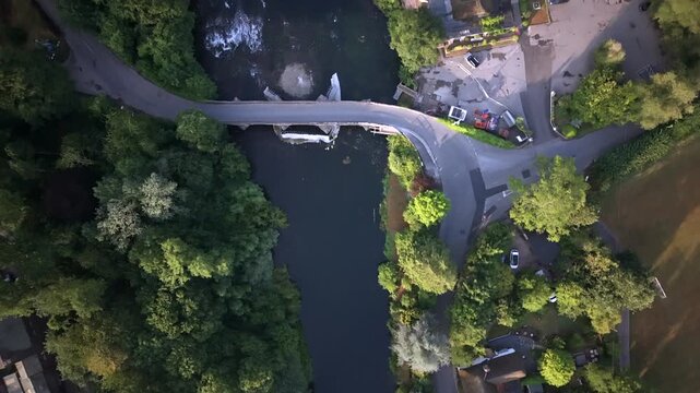 Aerial view of a bridge crossing a river beside riverside buildings in Bickleigh, near Tiverton, Devon.