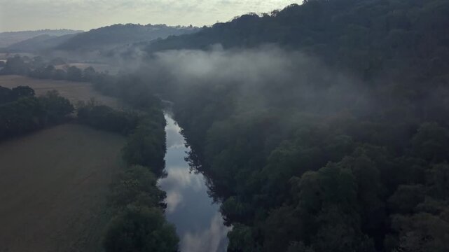 Aerial parallax pedestal shot over the River Exe, revealing a misty river valley near Bickleigh, Tiverton, Devon.