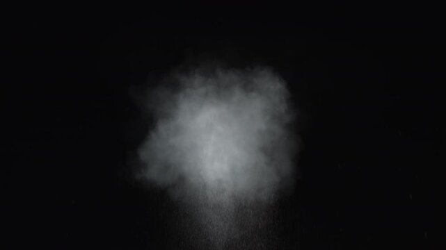 Dusty bullet impact on a wall sends chunks of debris and fine particles flying. White powder explosion bursts against a black, captured in dramatic slow motion close-up. Realistic VFX element
