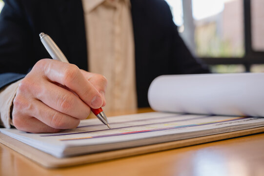 Businessman using pen analysing data charts on table in modern office in Business planning and investment financial data analytics graph Financial management technology concept.