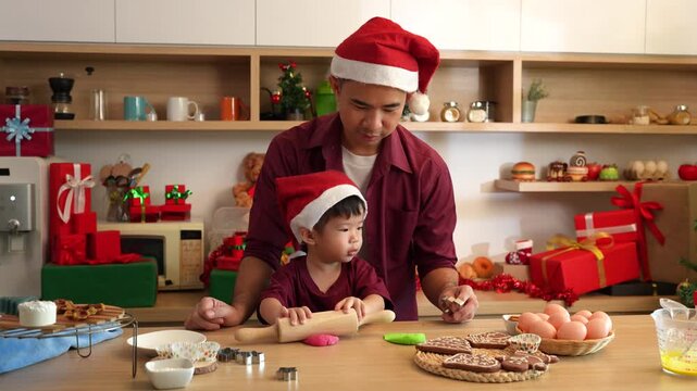 Christmas father helps child roll dough for cookies
