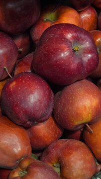 A close-up view of red apples stacked together. The apples vary in size and shade, showcasing a rich, vibrant color.