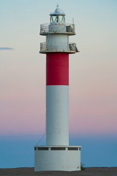 Lonely red and white lighthouse at pastel sunset